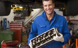 Mechanic holding car part smiling